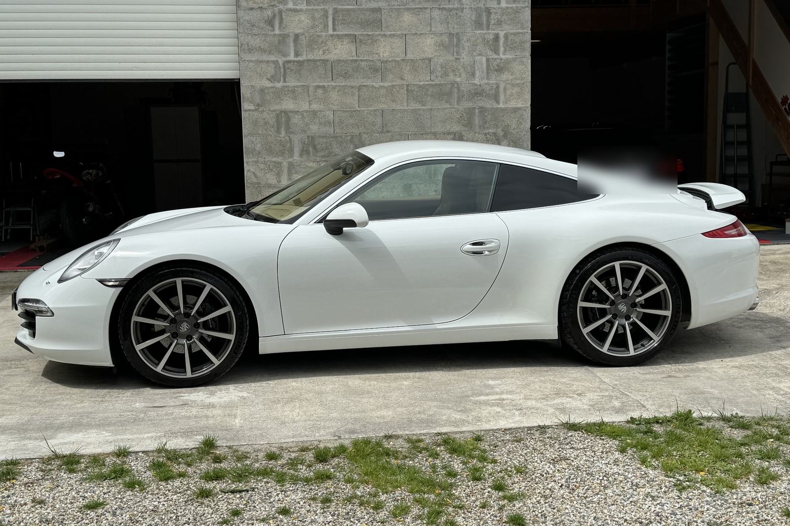 Une Porsche 911 blanche garée devant le garage